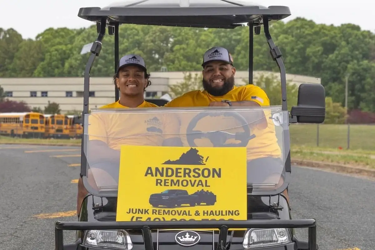 The Anderson Removal team in their branded cart with an Anderson Removal junk removal & hauling sign