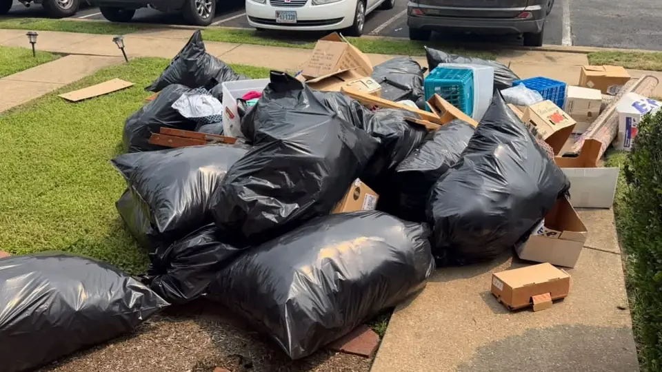 Before: a large pile of black trash bags and cardboard boxes on a front lawn and sidewalk
