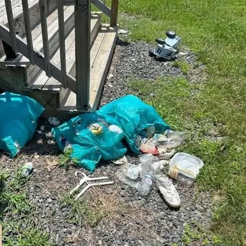 Before: bags of trash and debris on gravel beside deck steps