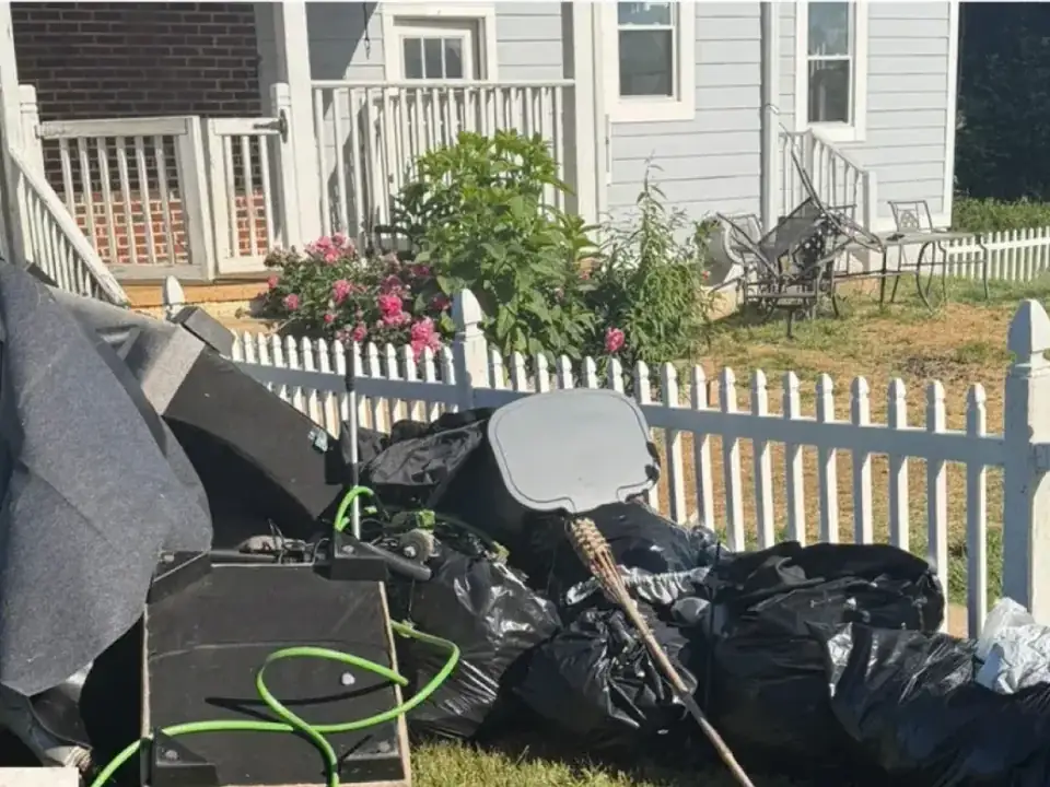 Before: furniture, bags and debris piled beside a white picket fence